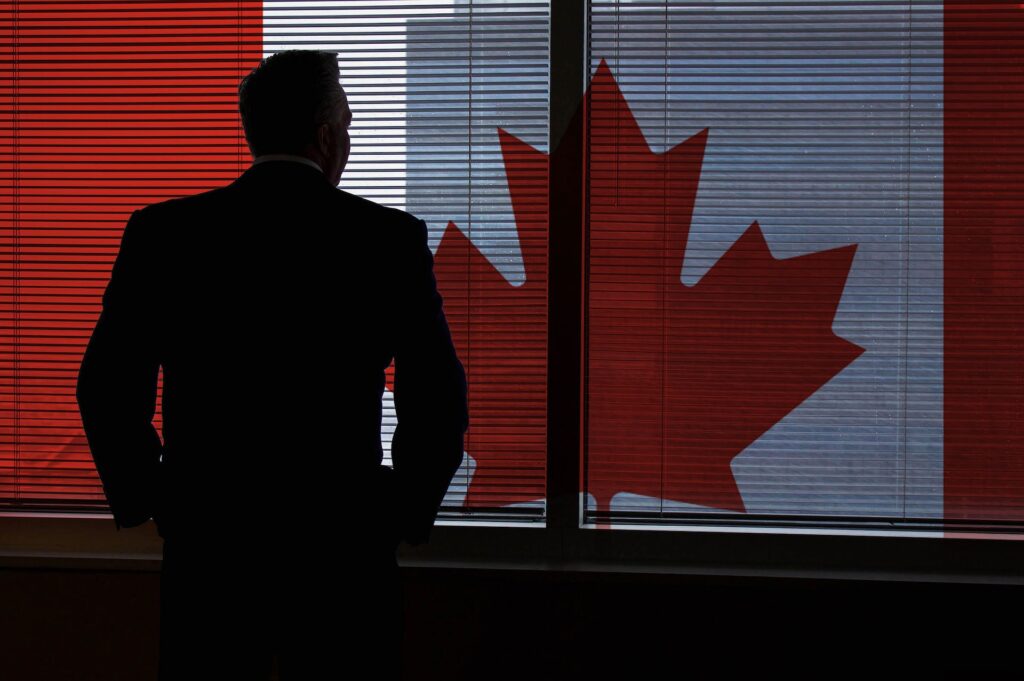 Successful man looking at Canadian flag through a window